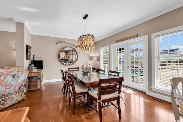 dining space with baseboards, visible vents, ornamental molding, wood finished floors, and french doors