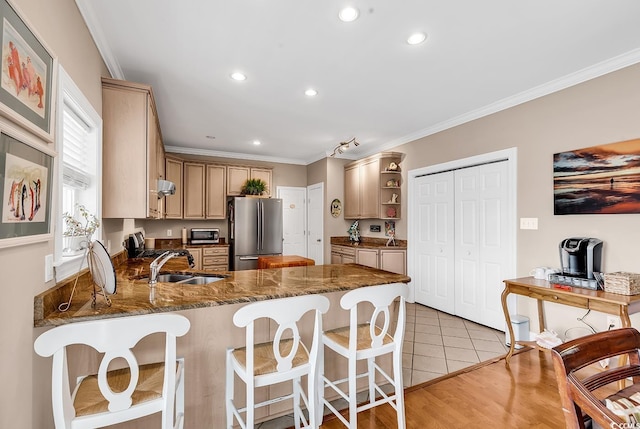 kitchen with open shelves, ornamental molding, freestanding refrigerator, a sink, and a peninsula