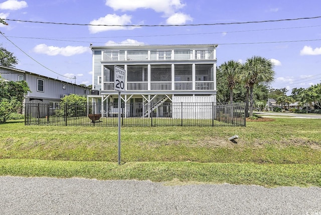 view of front of property featuring a sunroom, fence, a balcony, and a front lawn