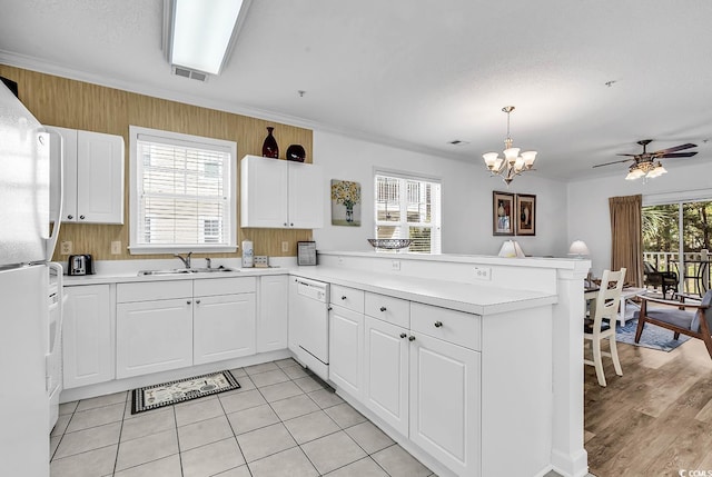 kitchen with a peninsula, white appliances, a healthy amount of sunlight, and light countertops