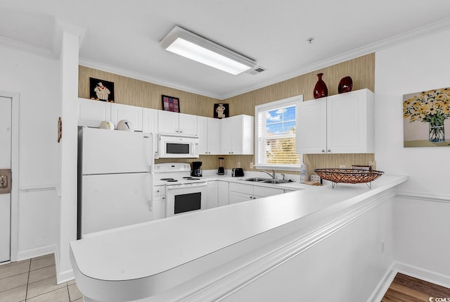 kitchen featuring a peninsula, white appliances, a sink, visible vents, and ornamental molding