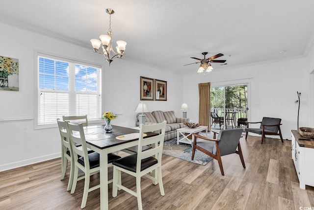 dining space featuring ornamental molding, light wood finished floors, ceiling fan with notable chandelier, and baseboards