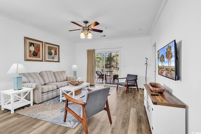 living area with ceiling fan, ornamental molding, visible vents, and light wood-style flooring