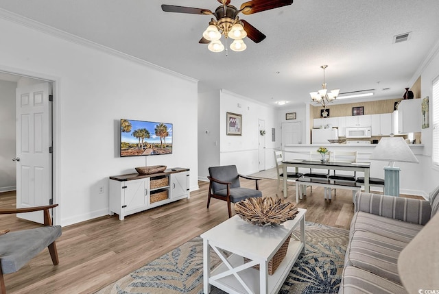 living area featuring a textured ceiling, visible vents, baseboards, light wood-style floors, and ornamental molding