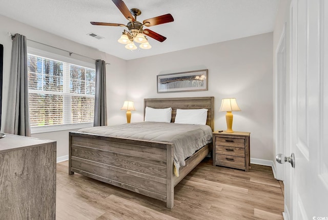 bedroom featuring a ceiling fan, baseboards, visible vents, and light wood finished floors