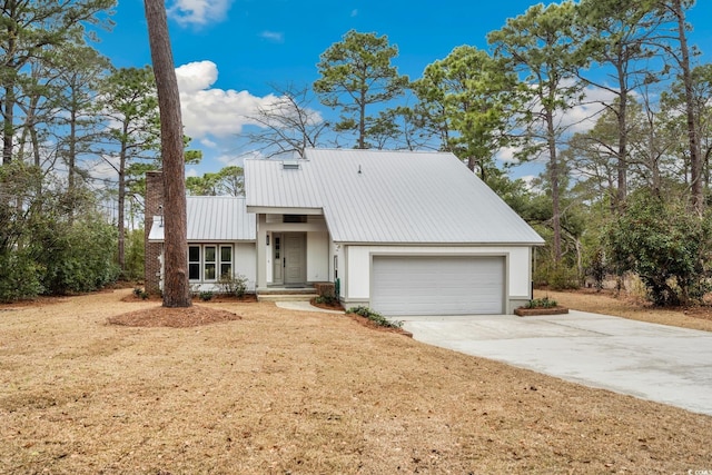 mid-century inspired home with concrete driveway, metal roof, and an attached garage