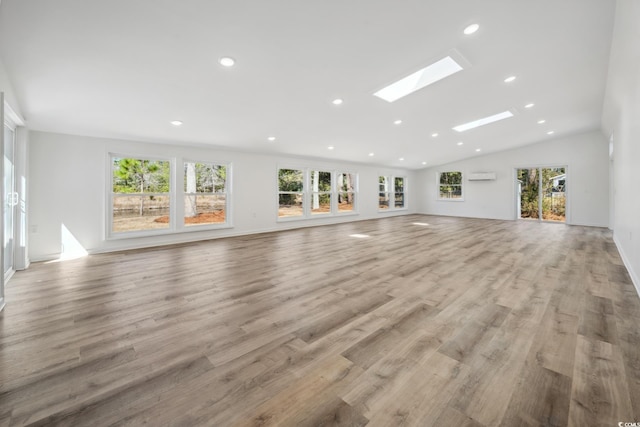 unfurnished living room featuring vaulted ceiling with skylight, wood finished floors, a wealth of natural light, and recessed lighting