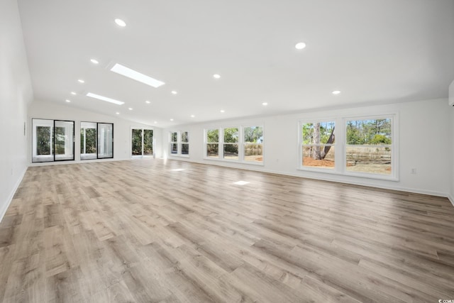 unfurnished living room featuring light wood-type flooring, vaulted ceiling with skylight, and a wealth of natural light