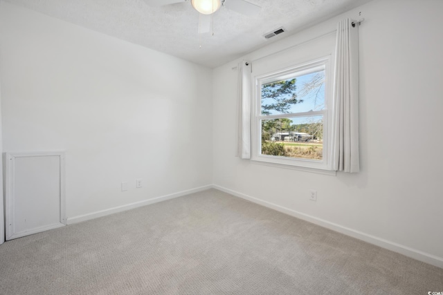 unfurnished room featuring carpet floors, visible vents, ceiling fan, a textured ceiling, and baseboards