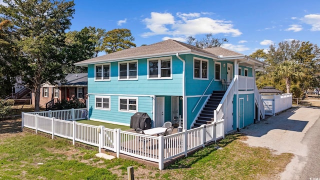 back of property featuring driveway, stairway, fence, and a lawn