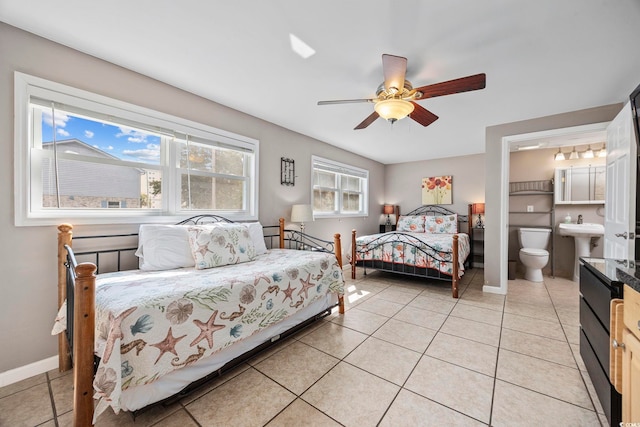 bedroom featuring light tile patterned floors, baseboards, a ceiling fan, and ensuite bath