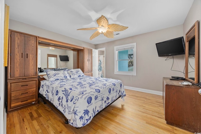 bedroom with light wood-style flooring, a ceiling fan, and baseboards