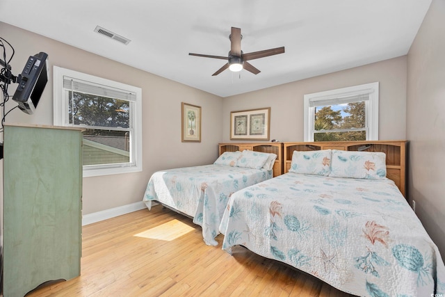 bedroom with a ceiling fan, visible vents, hardwood / wood-style floors, and baseboards