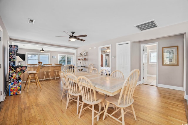 dining room featuring light wood finished floors, visible vents, and baseboards