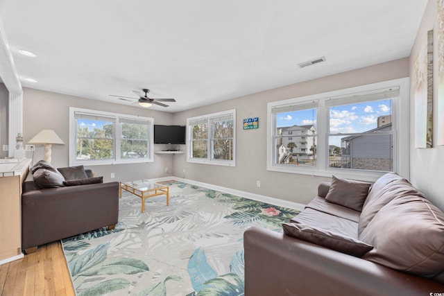 living room with baseboards, visible vents, ceiling fan, and wood finished floors