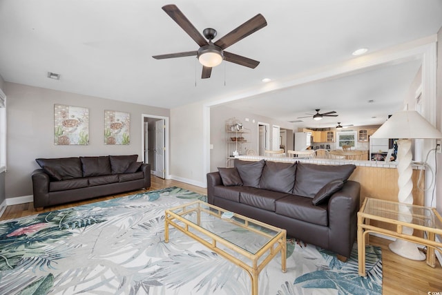 living area with recessed lighting, wood finished floors, a ceiling fan, visible vents, and baseboards