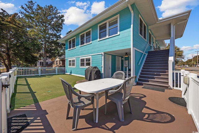 back of property featuring outdoor dining space, a patio area, a fenced backyard, and stairs