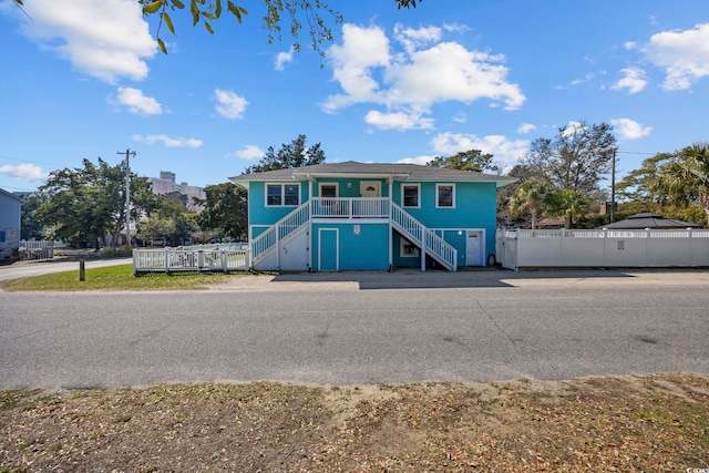 beach home with a porch, fence, and stairway