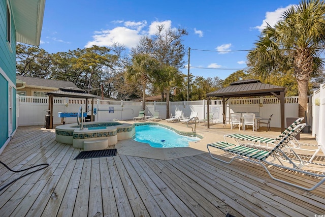 deck featuring a gazebo, a fenced backyard, and a pool with connected hot tub