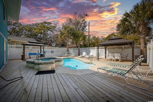 pool at dusk with a fenced backyard, a deck, and a gazebo