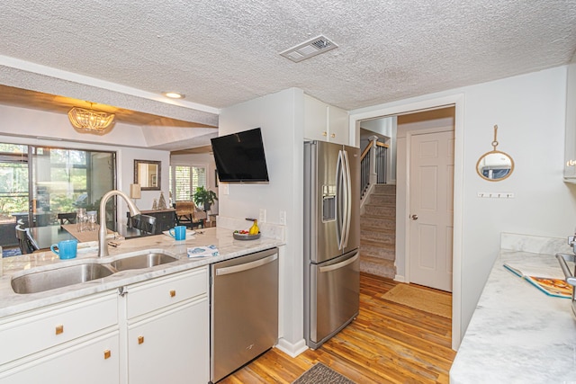 kitchen featuring light wood finished floors, visible vents, white cabinets, stainless steel appliances, and a sink