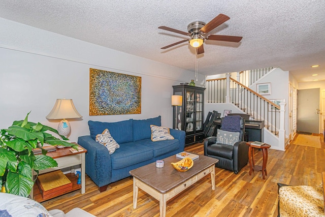 living room with a ceiling fan, wood finished floors, a textured ceiling, and stairs