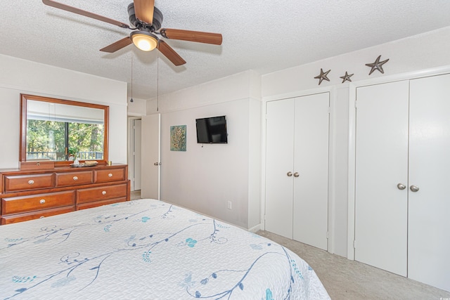 carpeted bedroom with a ceiling fan, a textured ceiling, and two closets