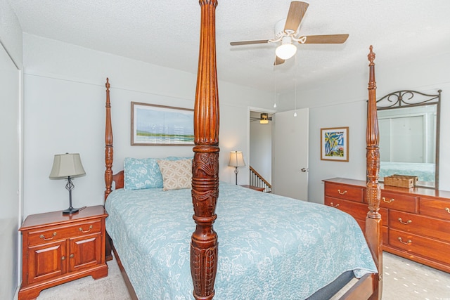 bedroom featuring a ceiling fan, light carpet, and a textured ceiling