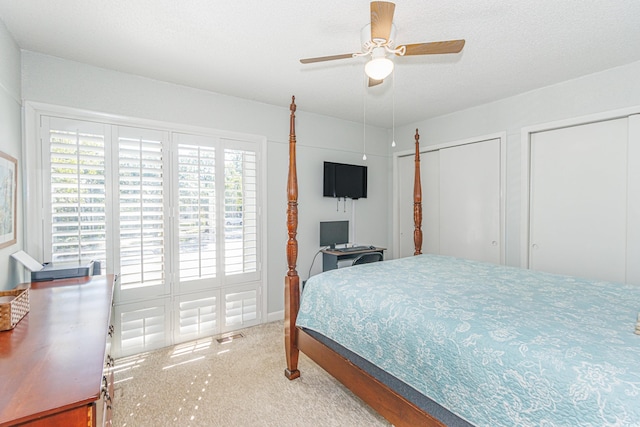 bedroom with ceiling fan, a textured ceiling, multiple closets, and carpet flooring