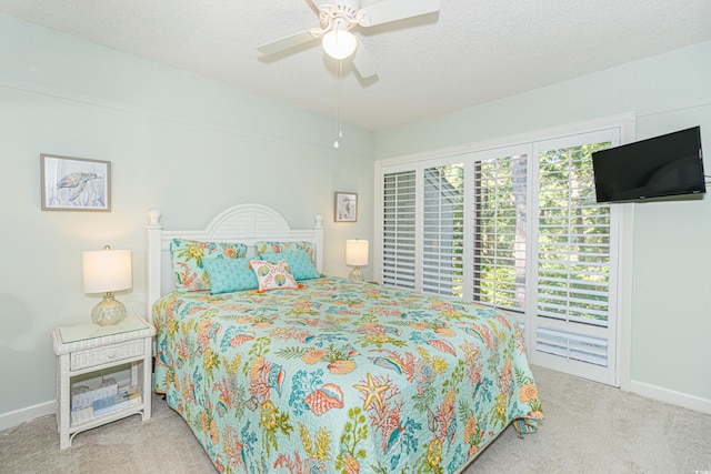 carpeted bedroom with a ceiling fan, a textured ceiling, and baseboards