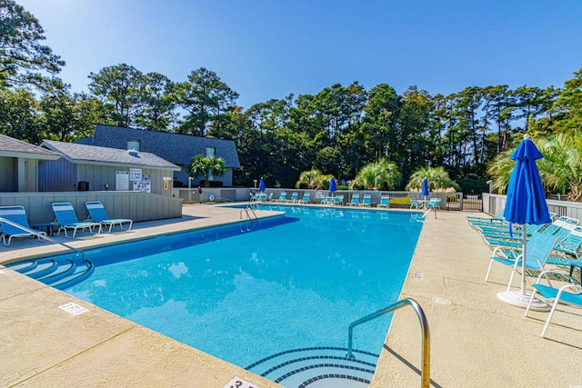 pool with a patio area and fence