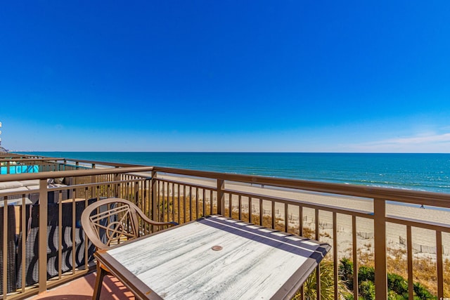 wooden terrace featuring a water view and a view of the beach