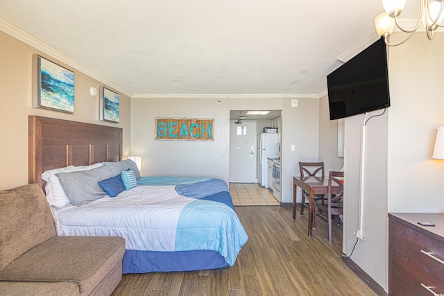 bedroom with ornamental molding, wood finished floors, and freestanding refrigerator