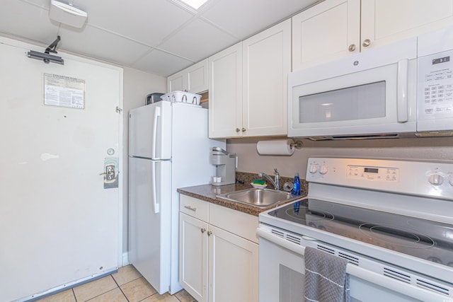 kitchen featuring a paneled ceiling, white appliances, white cabinets, and a sink