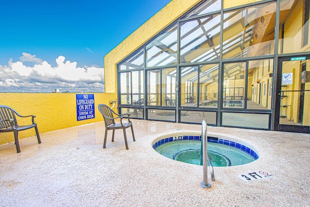 view of pool featuring glass enclosure, a patio, and an indoor hot tub