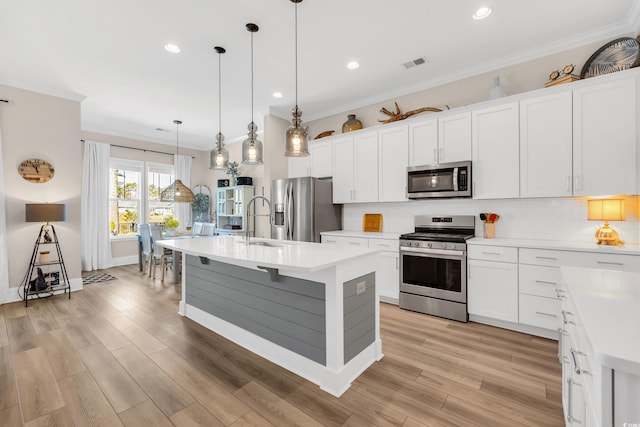 kitchen featuring stainless steel appliances, visible vents, ornamental molding, and decorative backsplash