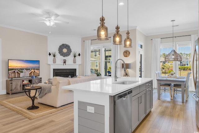 kitchen with ornamental molding, gray cabinetry, stainless steel dishwasher, a fireplace, and a sink