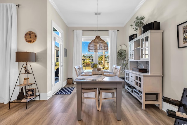 dining room with ornamental molding, baseboards, visible vents, and light wood finished floors