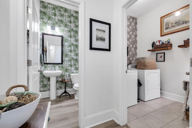 hallway featuring baseboards, washer / dryer, and wallpapered walls