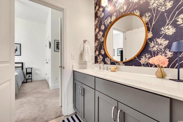 bathroom with baseboards, vanity, and wallpapered walls