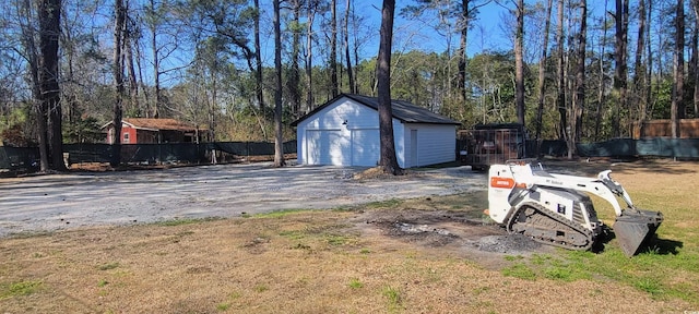 exterior space featuring an outbuilding, a detached garage, and fence