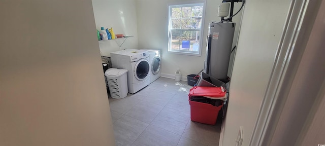 clothes washing area featuring laundry area, baseboards, washing machine and clothes dryer, tile patterned flooring, and water heater