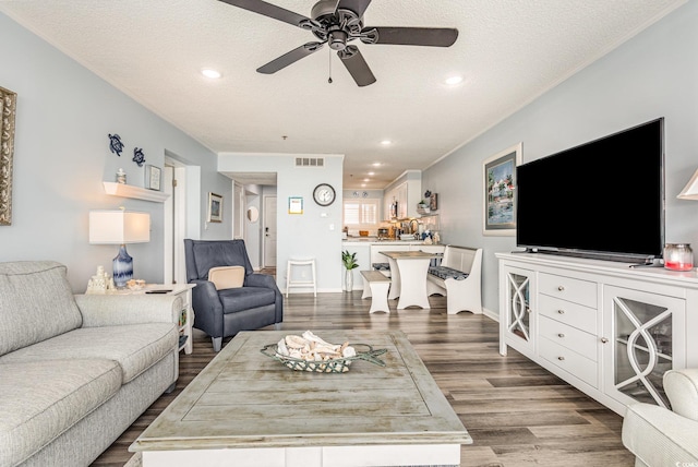 living area featuring a textured ceiling, wood finished floors, visible vents, and recessed lighting