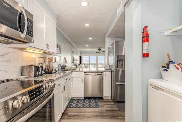 kitchen with appliances with stainless steel finishes, white cabinetry, backsplash, and wood finished floors