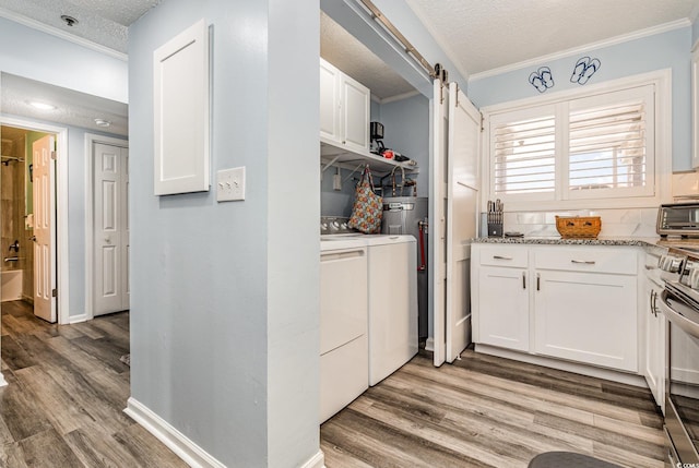 kitchen featuring a barn door, stove, white cabinetry, light wood-type flooring, and washing machine and clothes dryer