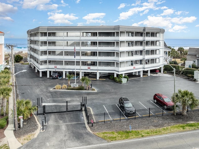 view of property with uncovered parking, a water view, and fence