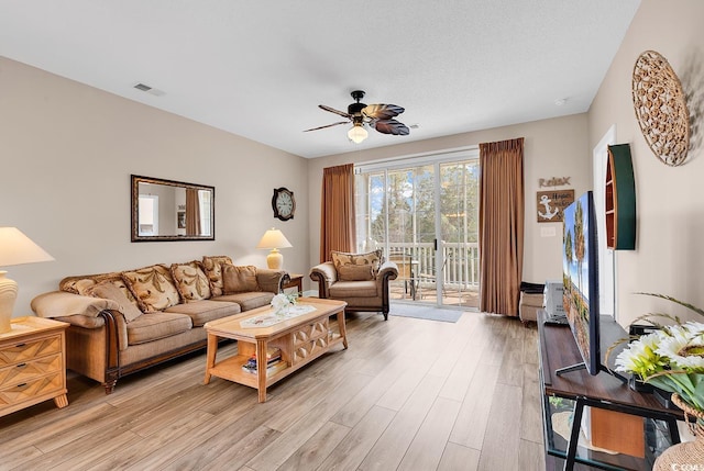 living room with a ceiling fan, light wood-type flooring, and visible vents