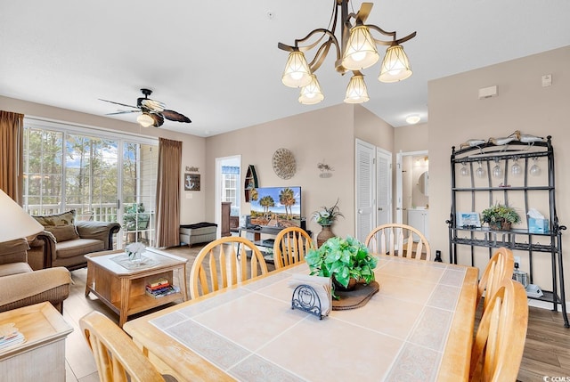 dining area with ceiling fan with notable chandelier, stacked washer / dryer, and wood finished floors