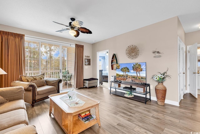 living room with light wood-style floors, a wealth of natural light, ceiling fan, and baseboards