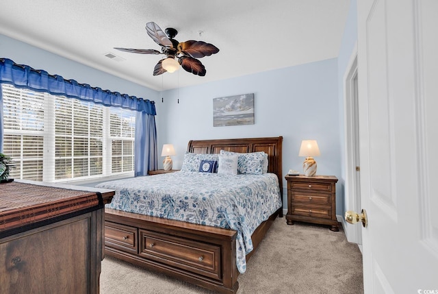 bedroom featuring ceiling fan, visible vents, and light colored carpet